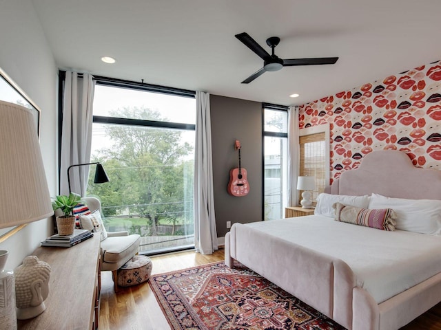 bedroom with a ceiling fan, light wood finished floors, and a wall of windows