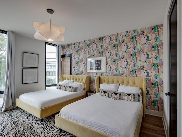 bedroom with baseboards, multiple windows, wallpapered walls, and wood finished floors