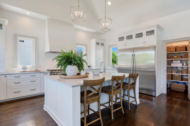 7314 Dug Hill Rd, Bon Aqua, TN 37025 - kitchen with stainless steel built in fridge, a chandelier, a center island with sink, white cabinets, and light stone countertops