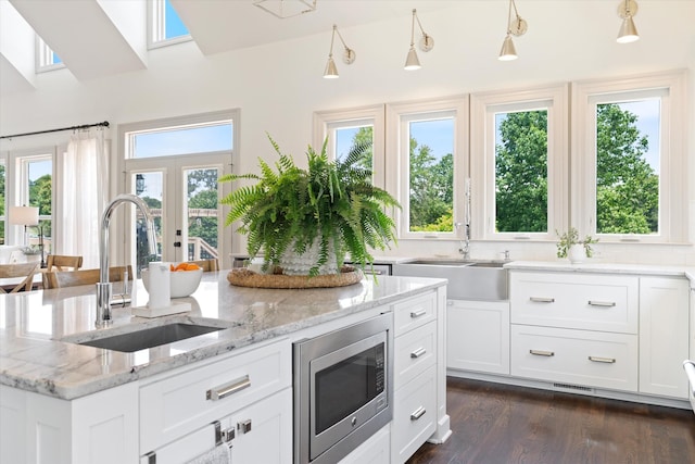 7314 Dug Hill Rd, Bon Aqua, TN 37025 - kitchen with stainless steel microwave, white cabinets, dark wood finished floors, light stone counters, and a center island with sink