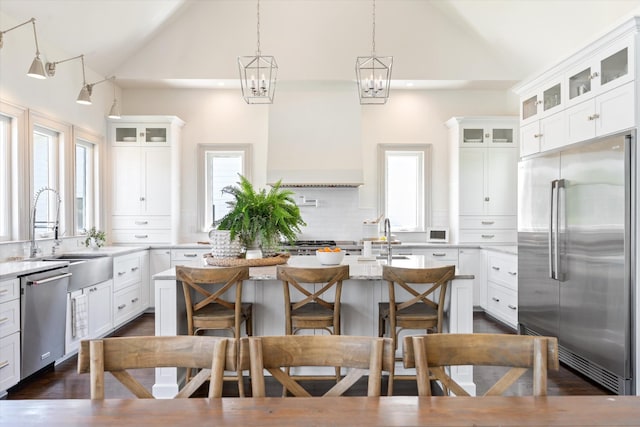 7314 Dug Hill Rd, Bon Aqua, TN 37025 - kitchen with stainless steel appliances, an island with sink, decorative backsplash, white cabinetry, and a kitchen breakfast bar