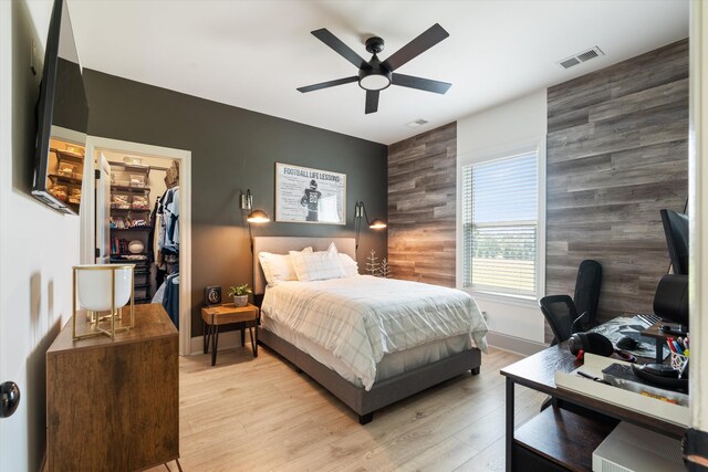 7314 Dug Hill Rd, Bon Aqua, TN 37025 - bedroom featuring an accent wall, an office area, light wood-style floors, a walk in closet, and wood walls