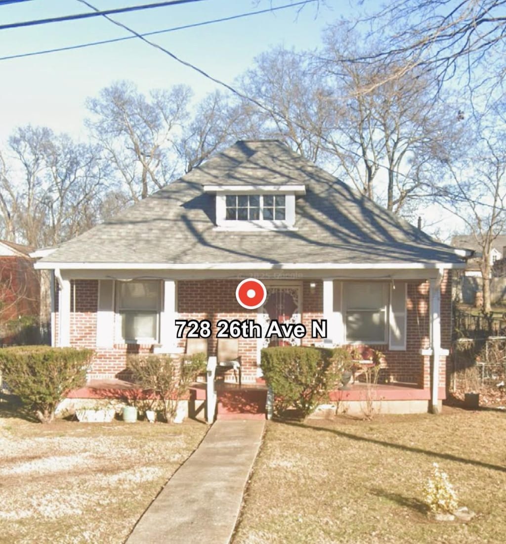 view of front of property with a porch, roof with shingles, and brick siding