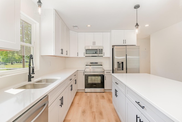kitchen with decorative light fixtures, visible vents, appliances with stainless steel finishes, a sink, and white cabinets