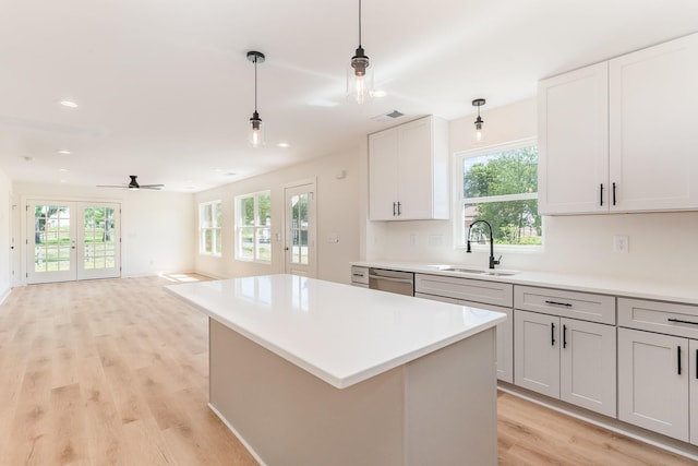 kitchen featuring a sink, dishwasher, a ceiling fan, light wood-type flooring, and pendant lighting