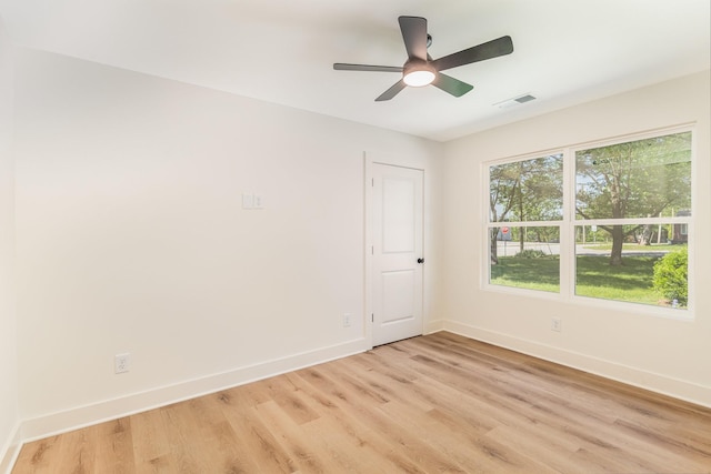 empty room with baseboards, ceiling fan, light wood finished floors, and visible vents
