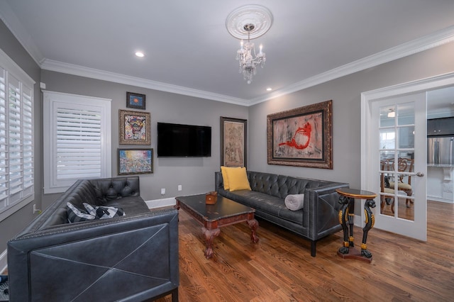 living area with crown molding, baseboards, a notable chandelier, and wood finished floors