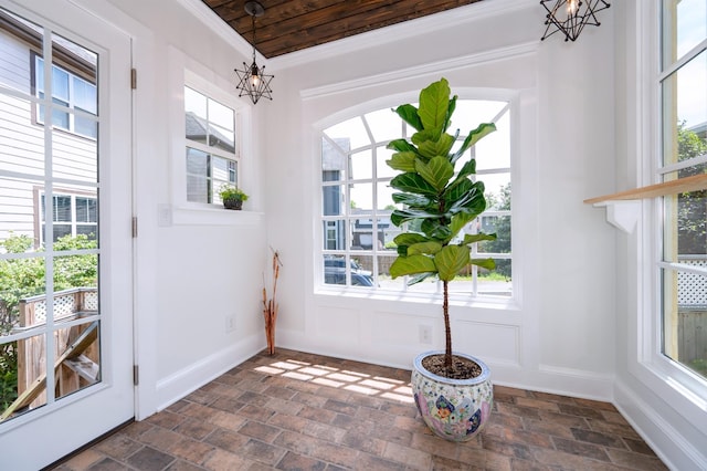 entryway with plenty of natural light, crown molding, and a notable chandelier