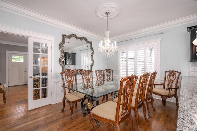 dining area with wainscoting, a notable chandelier, ornamental molding, and wood finished floors