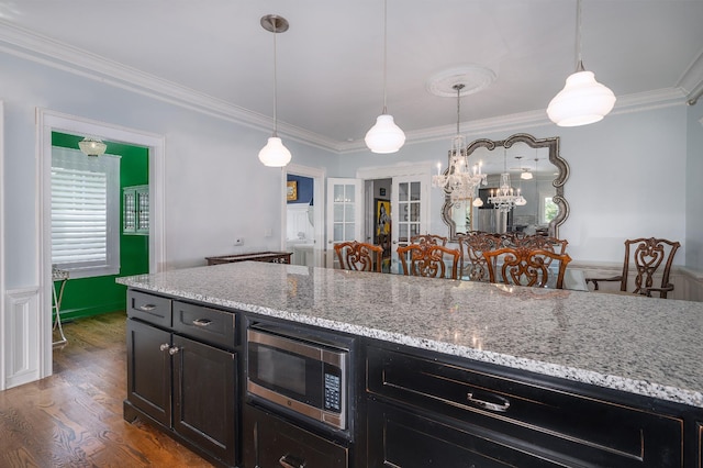 kitchen with ornamental molding, stainless steel microwave, wood finished floors, and a wainscoted wall