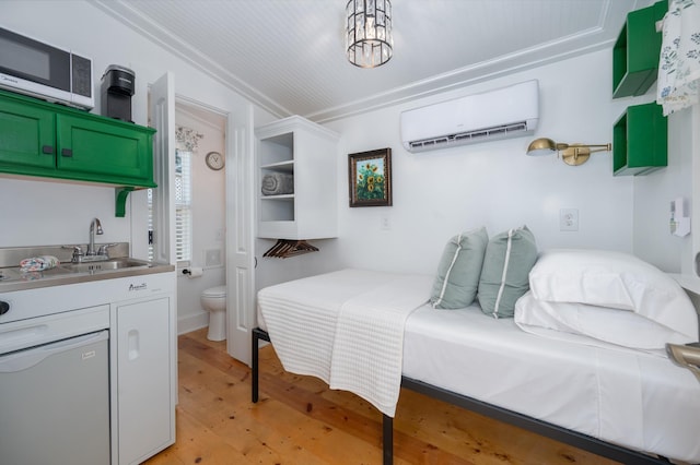 bedroom featuring a sink, ornamental molding, an AC wall unit, and light wood finished floors