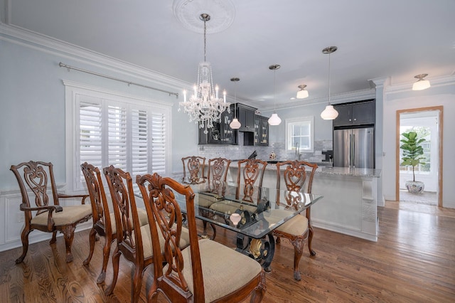 dining space with crown molding, a chandelier, and wood finished floors