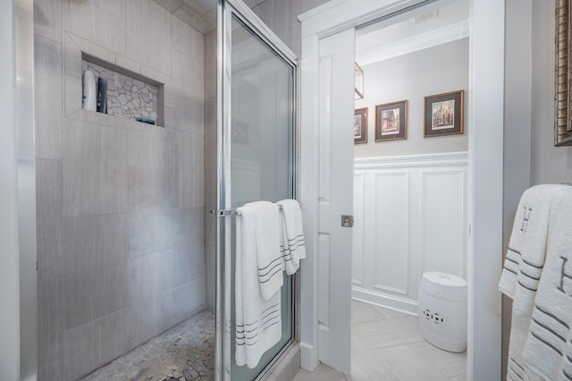 bathroom with wainscoting, a decorative wall, and a shower stall