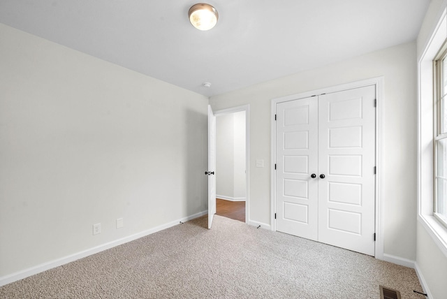 unfurnished bedroom with visible vents, carpet, multiple windows, and a closet