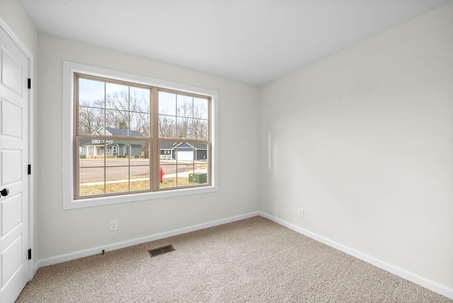 spare room with visible vents, carpet, and baseboards