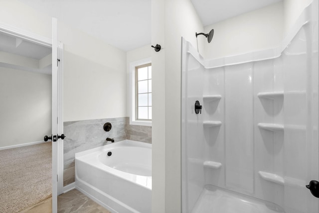 full bathroom featuring baseboards, a stall shower, and a bath