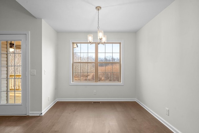 unfurnished dining area featuring visible vents, baseboards, a notable chandelier, and dark wood-style floors