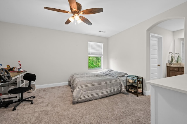 bedroom featuring arched walkways, light colored carpet, visible vents, and baseboards