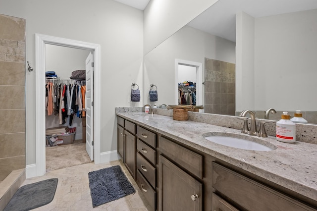 full bathroom with a sink, a tile shower, double vanity, and a spacious closet