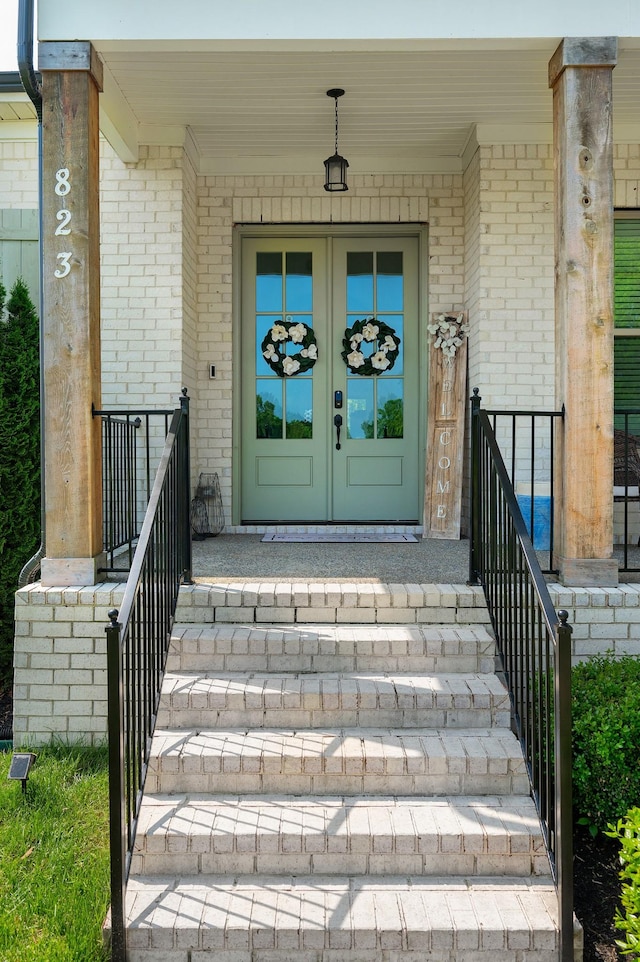 entrance to property with french doors, covered porch, and brick siding