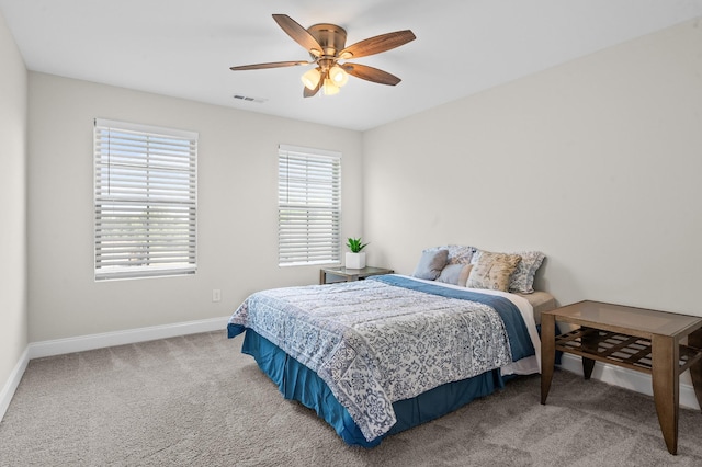 carpeted bedroom with baseboards, a ceiling fan, and visible vents