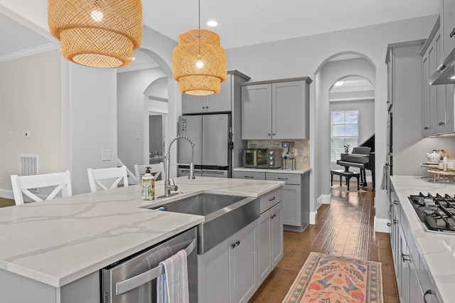 kitchen with gray cabinetry, arched walkways, and stainless steel appliances