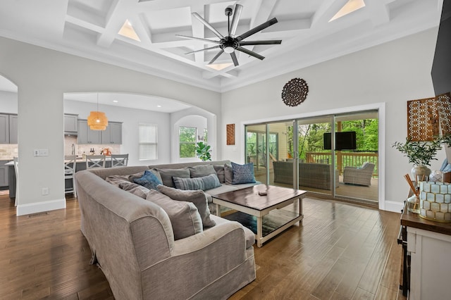 living room featuring arched walkways, coffered ceiling, dark wood finished floors, and a towering ceiling