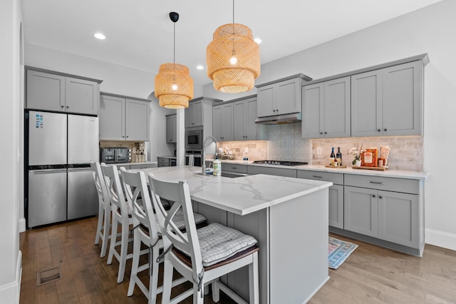 kitchen featuring backsplash, appliances with stainless steel finishes, gray cabinets, and light wood finished floors