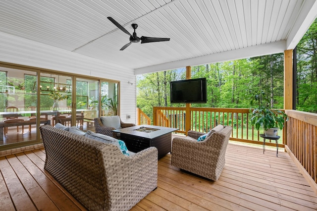 wooden deck featuring ceiling fan and an outdoor living space with a fire pit