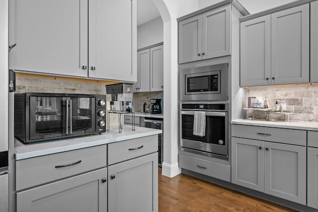 kitchen featuring light countertops, stainless steel appliances, decorative backsplash, and gray cabinets
