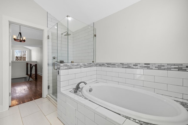 bathroom featuring tile patterned flooring, a bath, a notable chandelier, and a shower stall
