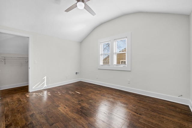 unfurnished bedroom featuring a closet, baseboards, vaulted ceiling, and dark wood finished floors