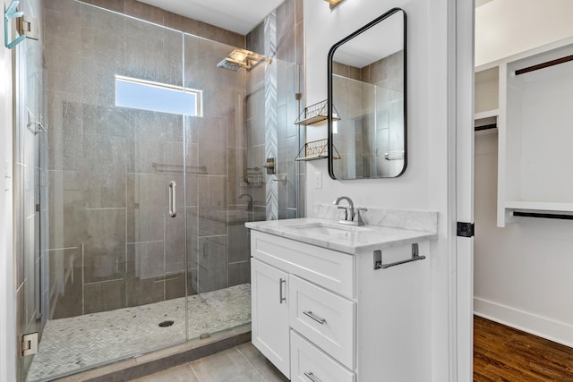 full bathroom with vanity, baseboards, a shower stall, and wood finished floors