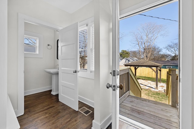 doorway to outside with baseboards, visible vents, and wood finished floors
