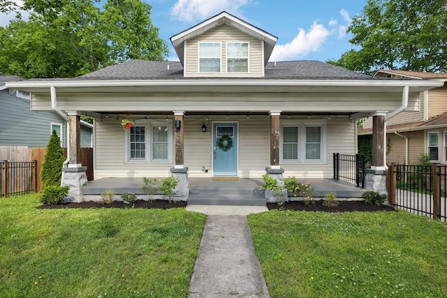 bungalow featuring roof with shingles, fence, covered porch, and a front yard