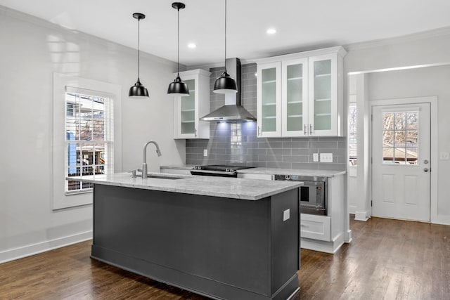kitchen with a sink, wall chimney exhaust hood, white cabinetry, and stainless steel appliances