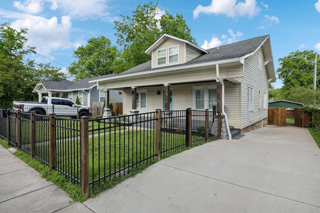 bungalow with roof with shingles, a fenced front yard, a front lawn, concrete driveway, and covered porch