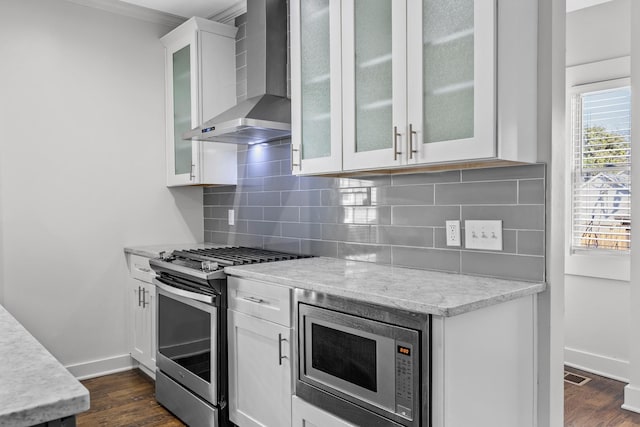 kitchen with wall chimney range hood, baseboards, stainless steel appliances, and dark wood-style floors