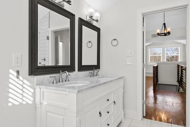 bathroom with baseboards, a sink, a chandelier, and visible vents