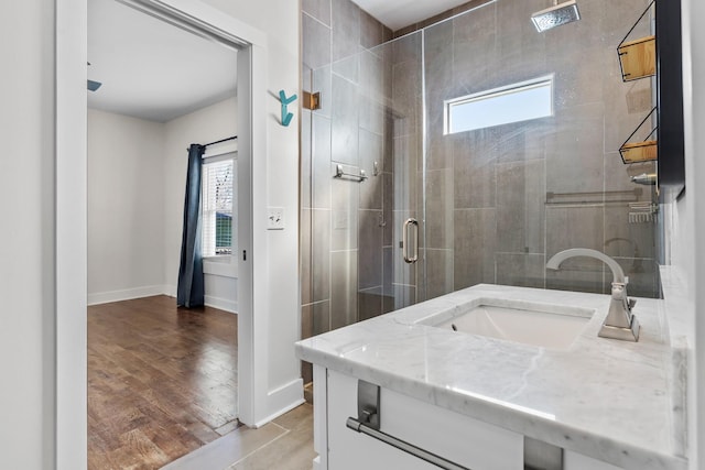 bathroom with baseboards, vanity, wood finished floors, and a shower stall