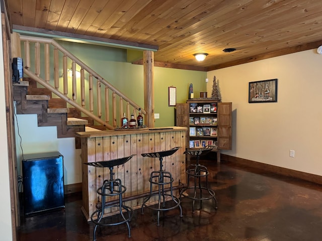 bar with a bar, stairs, wood ceiling, and baseboards