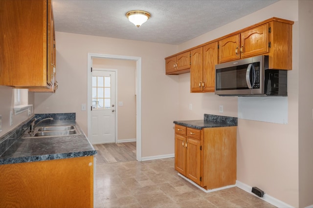 143 Willdon Dr, Portland, TN 37148 - kitchen featuring dark countertops, brown cabinets, a sink, baseboards, and stainless steel microwave