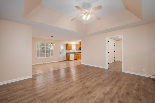 143 Willdon Dr, Portland, TN 37148 - unfurnished living room with a tray ceiling, baseboards, light wood finished floors, and ceiling fan with notable chandelier