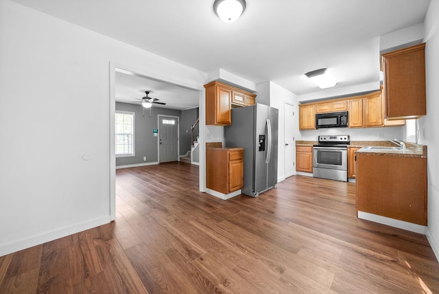 kitchen featuring baseboards, a sink, appliances with stainless steel finishes, and wood finished floors