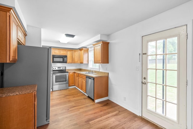 kitchen featuring a sink, light wood finished floors, a wealth of natural light, and stainless steel appliances