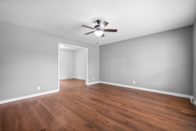 unfurnished room featuring a ceiling fan, baseboards, and dark wood-style floors