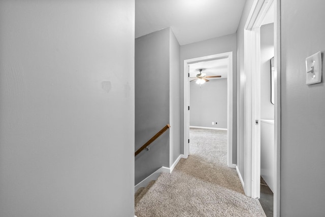 hallway with carpet floors, baseboards, and an upstairs landing