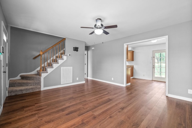 unfurnished living room featuring visible vents, dark wood-type flooring, ceiling fan, and stairway