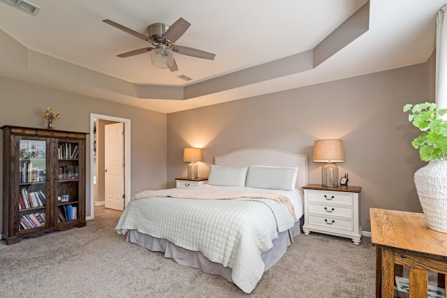 carpeted bedroom with baseboards, ceiling fan, a tray ceiling, and visible vents