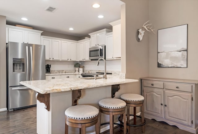 kitchen featuring a kitchen breakfast bar, stainless steel appliances, a peninsula, dark wood-type flooring, and visible vents